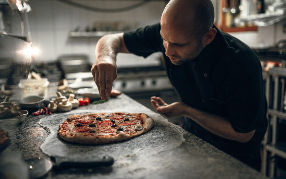 Le pizzaïolo en cuisine, garniture finale d'une pizza